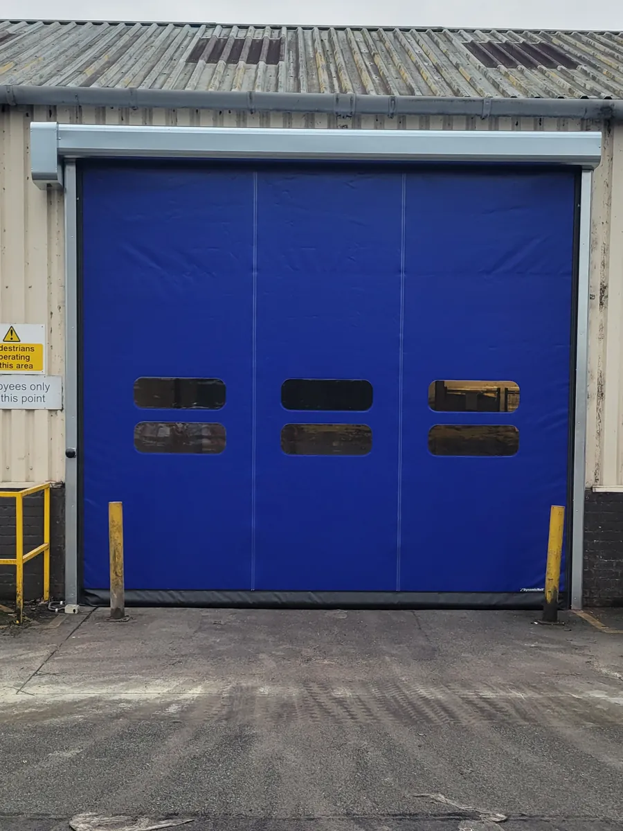 A blue high speed door with vision panels on an industrial unit